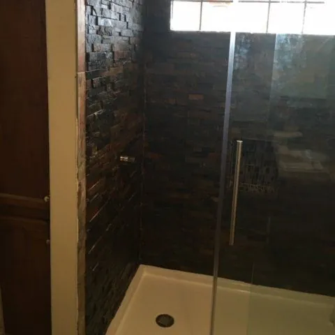 Dark stacked-slate shower wall with a glass door